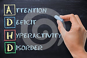 ADHD Ã¢â¬â attention deficit hyperactivity disorder handwritten by woman on blackboard photo